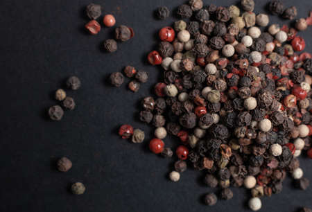 Spice allspice red, black and white peas scattered on a black backgroundの写真素材