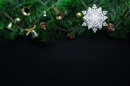 Christmas wreath decorated with a white snowflake and golden bells, balls, cones on a black...