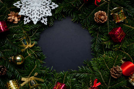 Christmas wreath decorated with a white snowflake, cones, red ball, red snowflake and beads on a black backgroundの写真素材