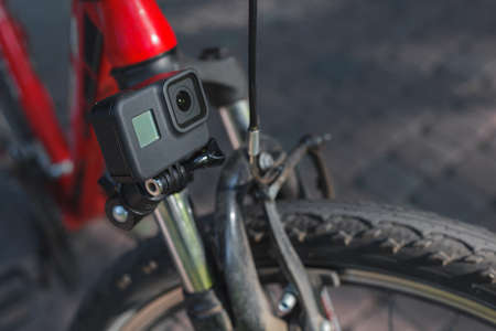 Action camera with a screen on, mounted next to a mountain bike wheelの写真素材