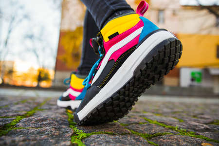 Sports multi-colored high boots on female legs in black jeans on the background of the cityの写真素材