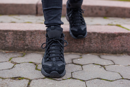 Black sneakers on the legs in black jeans at the girl on the street