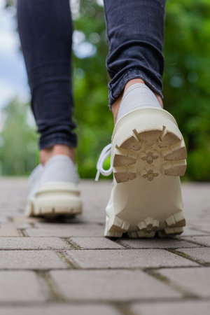 White sneakers with studded soles on female legs in black jeansの写真素材