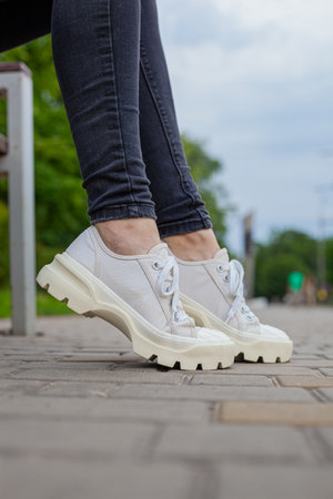 White sneakers with studded soles on female legs in black jeansの写真素材