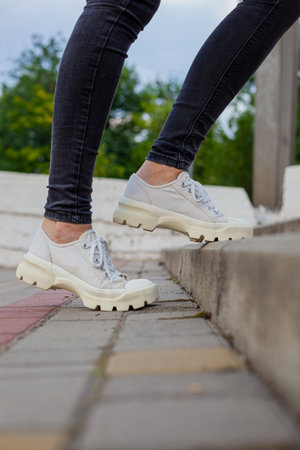 White sneakers with studded soles on female legs in black jeansの写真素材