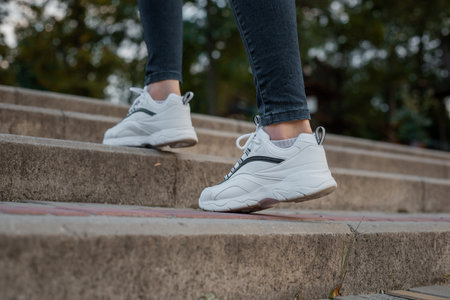 White sneakers on the feet of a girl in black jeans on the street