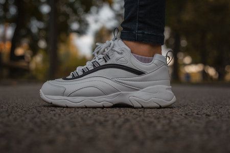 White sneakers on the feet of a girl in black jeans on the streetの写真素材