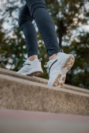 White sneakers on the feet of a girl in black jeans on the streetの写真素材