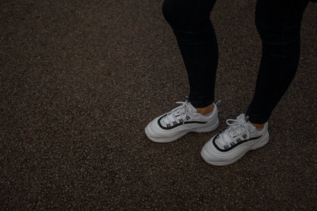 White sneakers on the feet of a girl in black jeans on the streetの写真素材