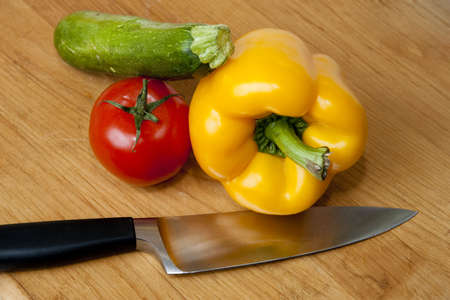 Bell pepper, tomato, and zuchini squash with knife on cutting boardの写真素材