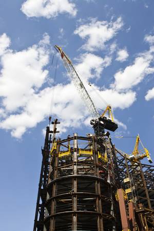 Tall skyscraper with crane assembling iron beams