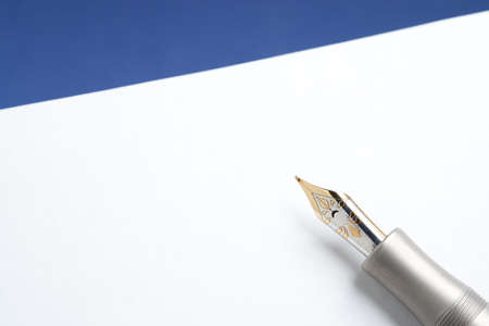 Gold and Titanium Fountain Pen on Stationery and Blue Backgroundの写真素材