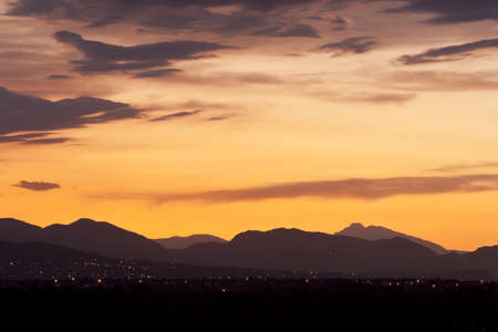 Vivid orange sunset over Colorado foothills. City lights dot hills in lower frame.の写真素材