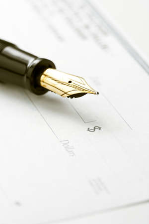 Fountain pen on blank check. Focus on tip of pen and dollar sign symbolの写真素材