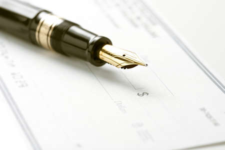 Fountain pen on blank check. Focus on tip of pen and dollar sign symbolの写真素材