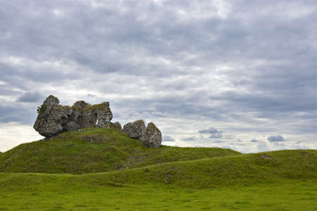 Old Castle in Republic of Ireland agains grassy hills and cloud filled sky