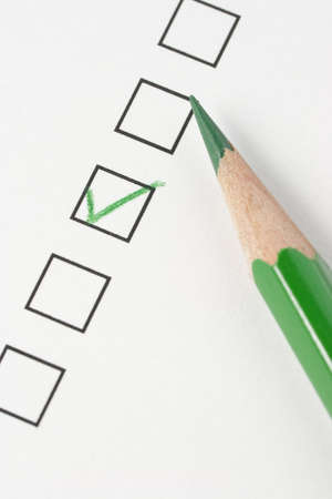 Survey with green pencil and check mark. Focus on pencil tip.