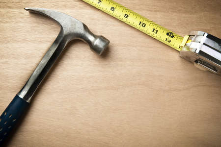 Hamer and measuring tape on wood background with copy space beneath and in middleの写真素材