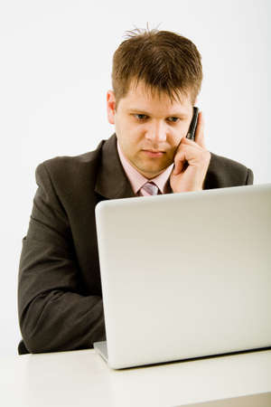Young businessman working with phone and laptop computerの写真素材