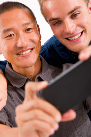 Close-up of two smiling friends taking self portrait with cell phoneの写真素材