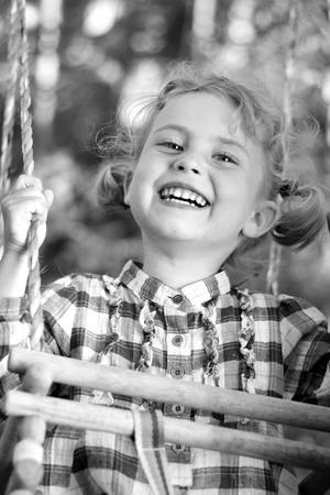 Little and pretty girl playing on a swingの写真素材