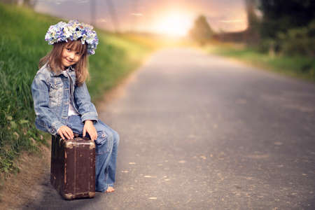  	Joyful little girl sitting on a suitcase - great tripの写真素材