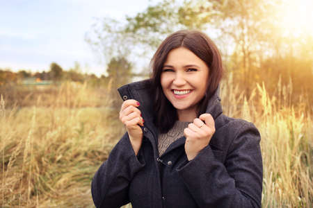 lovely girl in a jacket laughs on a sunny afternoonの写真素材