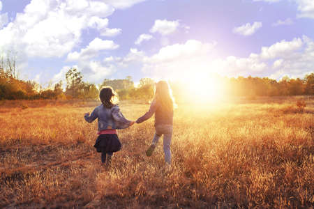 Two young girls runs on the sunny meadowの写真素材