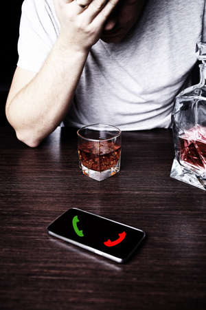 Drunk man in front of a mobile phoneの写真素材