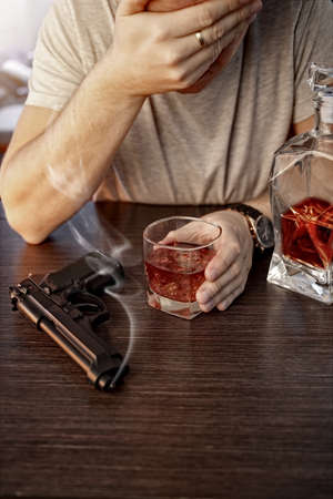 Devastated man with a gun and alcoholの写真素材