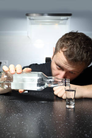 drunk man pours a glass of vodka