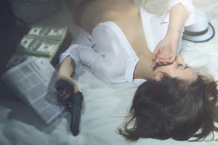 Girl in hotel room with gun and moneyの写真素材
