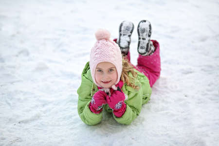 Cheerful young girl lying in the snowの写真素材