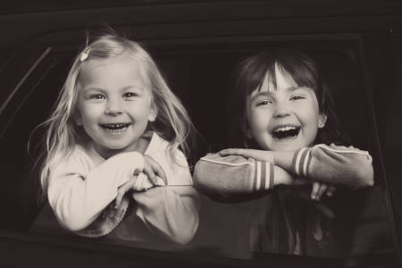 smiling and charming children look through the glass in the carの写真素材