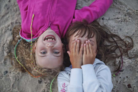 Young friends laughing lying on the beachの写真素材