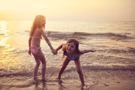 Two young girls playing on the beachの写真素材