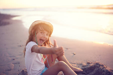 Young girl in a hat shows thumbs upの写真素材