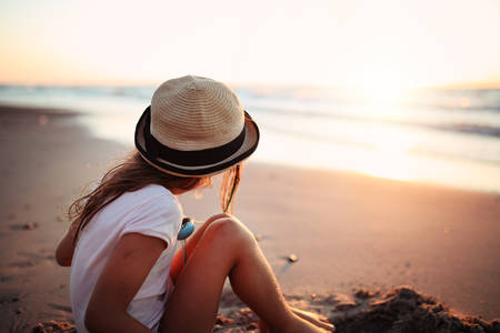girl in a hat sitting on the seashoreの写真素材