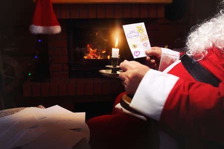 Santa Claus reads letters written by children around the fireplaceの写真素材