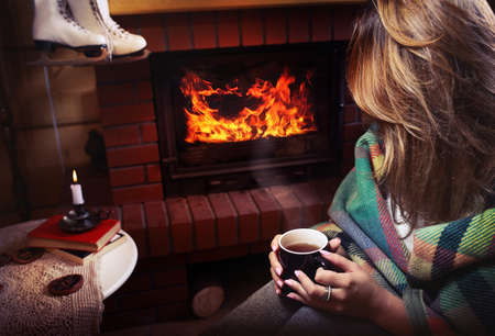 Young woman heated front of the fireplace