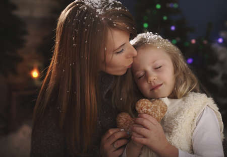 Mom and daughter cuddle in winter evening