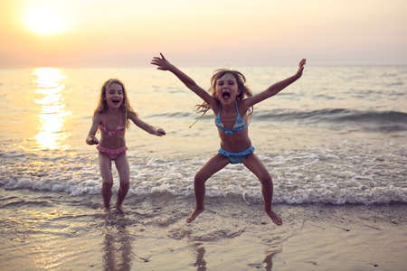 Two sisters playing on the beach at sunsetの写真素材