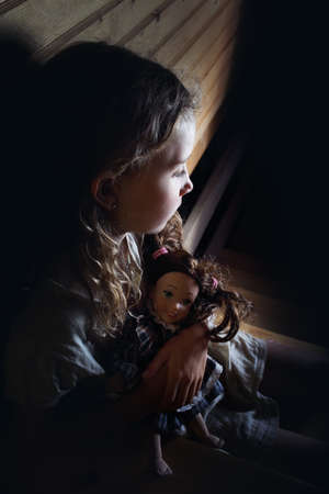 lonely little girl cuddles a doll