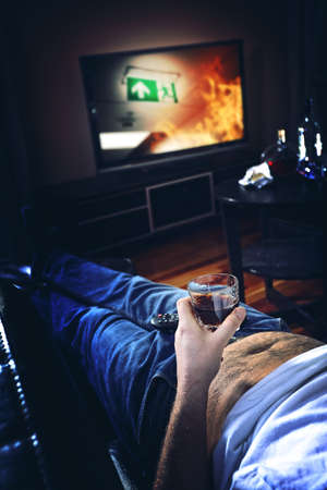 Man lies on the couch and drinks alcoholの写真素材