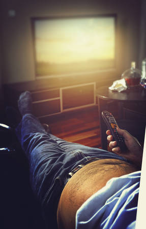 Guy on the couch flips channels on tvの写真素材