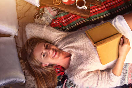 Happy woman with tea with lemon and bookの写真素材