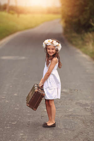 Happy young girl in a wreath on the roadの写真素材