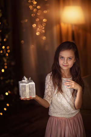 Young girl in Christmas evening holding a giftの写真素材
