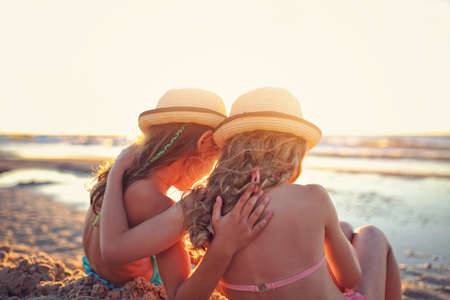 Two young girls talk  and have fun on the beachの写真素材
