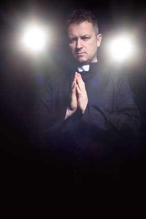 praying priest on black backgroundの写真素材